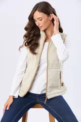 Chaleco de tejido sherpa color beige, con cuello alto y detalles en eco cuero. Diseño sin mangas que proporciona abrigo al torso manteniendo la libertad de movimiento.