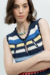 Vestido corto tejido a crochet con rayas horizontales en colores azul, amarillo, marrón, blanco y rosa. Presenta escote redondo con abertura en forma de gota y terminaciones con puntilla.