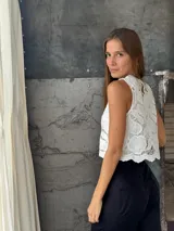 Blusa sin mangas color blanco, con cuello redondo y confeccionada completamente en tejido de encaje con motivos florales.