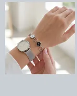 Pulsera de acero con eslabones circulares y dijes en forma de flor esmaltados en blanco y negro.