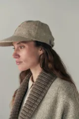 Gorra con visera confeccionada en lana fina sin teñir, con un sutil patrón de tejido en espiga.