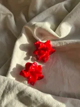 Par de aros tipo caravanas con diseño de flor en color rojo brillante, realizados artesanalmente en porcelana.