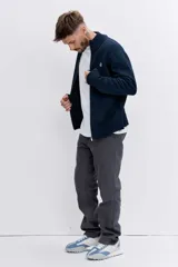 Cardigan de punto color azul marino, con cierre frontal completo, cuello alto y puños acanalados. Presenta un pequeño bordado distintivo en el pecho.