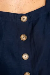 Top corto color rojo, con escote cuadrado y tirantes anchos. Presenta una hilera de botones marrones en el centro del frente.