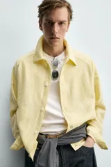 Sobrecamisa relaxed fit de color amarillo claro, confeccionada en tejido con mezcla de lyocell. Presenta cuello solapa, mangas largas raglán con puños abotonados, bolsillos de vivo en la cadera y cierre frontal con botonadura.