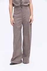 Pantalón de pierna amplia y tiro alto, confeccionado en tejido a rayas con una mezcla de algodón, poliéster y lino. Presenta un diseño de corte sastrero con bolsillos laterales y trabillas para cinturón.