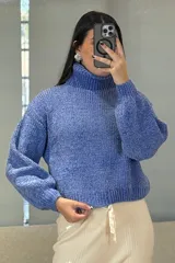 Buzo de chenille color blanco, con cuello alto tipo polera, mangas largas con puños ajustados y diseño de tejido acanalado.