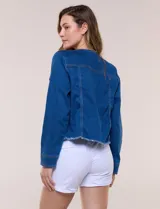 Campera de denim azul oscuro con cuello mao, cierre frontal de botones metálicos, bolsillos plaqué con solapa en el pecho y detalle desflecado en el ruedo.