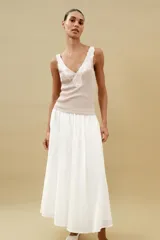 Top de punto canalé en color beige, con escote en pico adornado con una delicada aplicación de encaje blanco y tirantes anchos.