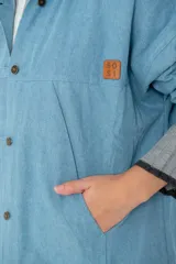 Campera de jean oversize color azul claro, con cuello camisero, cierre frontal con botones y bolsillos frontales. Presenta un diseño de corte amplio y cómodo con mangas largas.