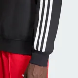 Buzo Adidas negro de cuello redondo, con las tres tiras blancas características de la marca en las mangas y el logo del trébol en el pecho.