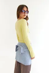 Top de manga larga color amarillo, confeccionado en tejido acanalado con cierre frontal de botones a presión metálicos. Presenta detalles de botones en los puños y un corte ajustado al cuerpo.