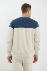 Sweater deportivo de hombre con escote redondo, diseño colorblock con la parte superior en gris claro y el cuerpo y mangas en negro. Presenta puños y cintura elastizados.