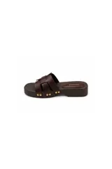 Sandalia tipo zueco Paddock de color negro, con plataforma baja de aspecto amaderado y tiras entrelazadas en el empeine. Presenta detalles de tachas metálicas doradas en los laterales y plantilla acolchada.