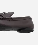 Mocasín femenino estilo penny loafer confeccionado en cuero, con suela baja y diseño estructurado con recorte en el empeine.