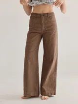 Pantalón de tiro medio alto color marrón, con bolsillos delanteros y traseros, y detalles de atraques y triples costuras en diferentes colores.