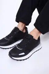 Championes urbanos de diseño deportivo en color negro, confeccionados en poliuretano con paneles de malla. Presentan suela de goma blanca con detalles en gris y cierre mediante cordones al tono.