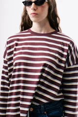 Camiseta de manga larga con diseño de rayas horizontales en tonos bordó, blanco y amarillo. Presenta un corte holgado y relajado con cuello redondo.