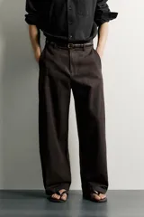 Pantalón barrel fit de corte ancho color marrón, confeccionado en mezcla de algodón y lino. Presenta bolsillos frontales, bolsillos traseros de vivo y cierre frontal con cremallera y botón.