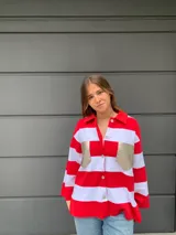 Camisa de manga larga a rayas horizontales rojas y blancas, con cuello camisero, cierre frontal con botones y dos bolsillos dorados en el pecho.