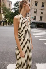 Vestido midi de cuello halter anudado, escote en pico y espalda descubierta, con diseño a rayas verticales y bajo abullonado con elástico interior.