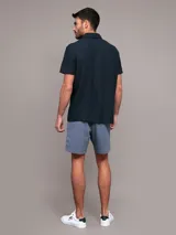 Chomba de manga corta Calvin Klein color azul marino, con cuello polo y cierre frontal parcial con cremallera. Presenta una banda horizontal en el pecho con el logo de la marca bordado.