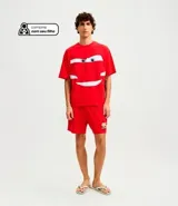 Pijama corto de hombre confeccionado en algodón, compuesto por una remera de manga corta con cuello redondo y estampa frontal de Rayo McQueen, y una bermuda roja a juego con cintura elástica.