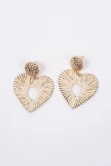 Aros colgantes en forma de corazón, compuestos por una pieza superior circular de metal dorado con textura martillada y una estructura inferior en forma de corazón tejida con hilo de fibra natural en color crema.