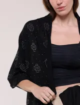 Pashmina ligera de color negro, de forma rectangular, con aplicaciones de brillos formando patrones geométricos.