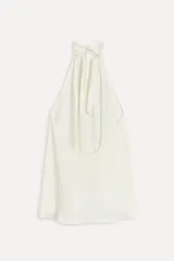 Top blanco de viscosa con cuello halter ajustable con lazadas y espalda descubierta.