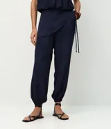 Pantalón modelo aladim confeccionado en jacquard de viscosa, con diseño floral en relieve, cintura elástica y superposición asimétrica en el delantero que forma un canesú redondeado.