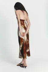 Vestido largo de corte recto con cuello halter y escote redondo, confeccionado en tela satinada con estampado abstracto en tonos tierra y bordó.