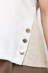 Remera blanca sin mangas con escote en V, detalles de botones en el lateral y espalda de tejido de punto en tono tostado.