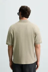 Polo de tejido canalé en color blanco, con cuello solapa y abertura frontal en V, de manga corta y corte regular.