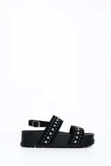 Sandalia chunky de plataforma color negro, con diseño de doble tira ancha decorada con tachas metálicas cónicas y pulsera ajustable al tobillo con hebilla.