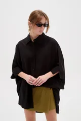 Camisa de lino blanca de corte holgado, con cuello camisero y mangas tres cuartos, diseñada con estilo casual.
