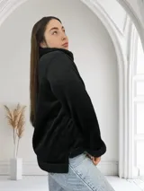 Campera negra de pana con cuello, puños y ruedo de corderito sintético. Cierre frontal con cremallera plateada.