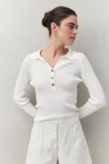 Sweater azul marino de punto acanalado con cuello tipo polo y botonadura frontal dorada. Mangas largas con aberturas en los puños.