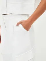 Pantalón de vestir blanco, de tiro alto y corte palazzo, con bolsillos laterales y bolsillos cargo con solapa en los muslos.