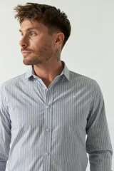 Camisa de hombre de corte slim fit, confeccionada en algodón con diseño de rayas verticales finas en tonos claros. Presenta cuello clásico, cierre frontal con botones y logo bordado en el pecho.
