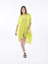 Vestido camisero de corte holgado y diseño asimétrico, con cuello clásico, cierre frontal de botones y mangas cortas con terminación caída.