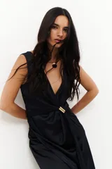 Vestido midi marrón con escote en V, sin mangas y detalle de nudo con aro dorado en la cintura.