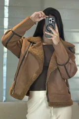 Campera tipo gamulán de color crema con interior y cuello de corderito sintético. Presenta cierre frontal cruzado, bolsillos laterales con cierre y detalles de costuras en contraste color marrón oscuro.