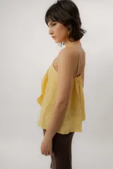 Musculosa de lino color amarillo, con tirantes finos, escote redondo y detalle de volados frontales.