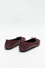 Balerinas negras de símil cuero texturizado con aplique de moña y detalles metálicos.