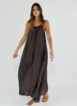 Vestido largo de corte holgado y fluido, con escote redondo y breteles finos. Presenta un diseño minimalista con textura arrugada.