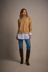 Sweater tejido color marrón claro, de escote redondo y calce holgado. Tiene hombros caídos, mangas largas y puños tejidos.