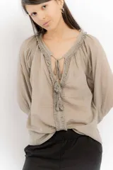 Blusa celeste de algodón con escote en V con lazos y mangas largas abullonadas con puños elásticos.