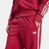 Pantalón deportivo Adidas Firebird Drop Needle de color rojo con rayas verticales finas, bolsillos laterales con cierre y las icónicas tres tiras blancas a lo largo de los laterales. Incluye el logo del trifolio bordado en la pierna.