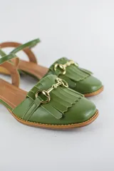Sandalias de cuero color celeste, con punta cerrada, flecos frontales y detalle de estribo metálico dorado. Tienen tira ajustable al tobillo y suela plana con pequeño taco.